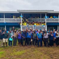 MEHRD, DFAT and MPG delegation along with Malaita Education Officers posing with cheerful students in front of the newly built 8-block classroom building.