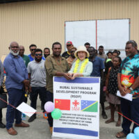 Counsellor Li Qinghua of the Chinese Embassy in Solomon Islands and West Makira Constituency Development Officer Selwyn Aharo cut the ribbon to officially launch and hand over the project, as MRD Permanent Secretary John Misite'e, officials, and beneficiary representatives look on.